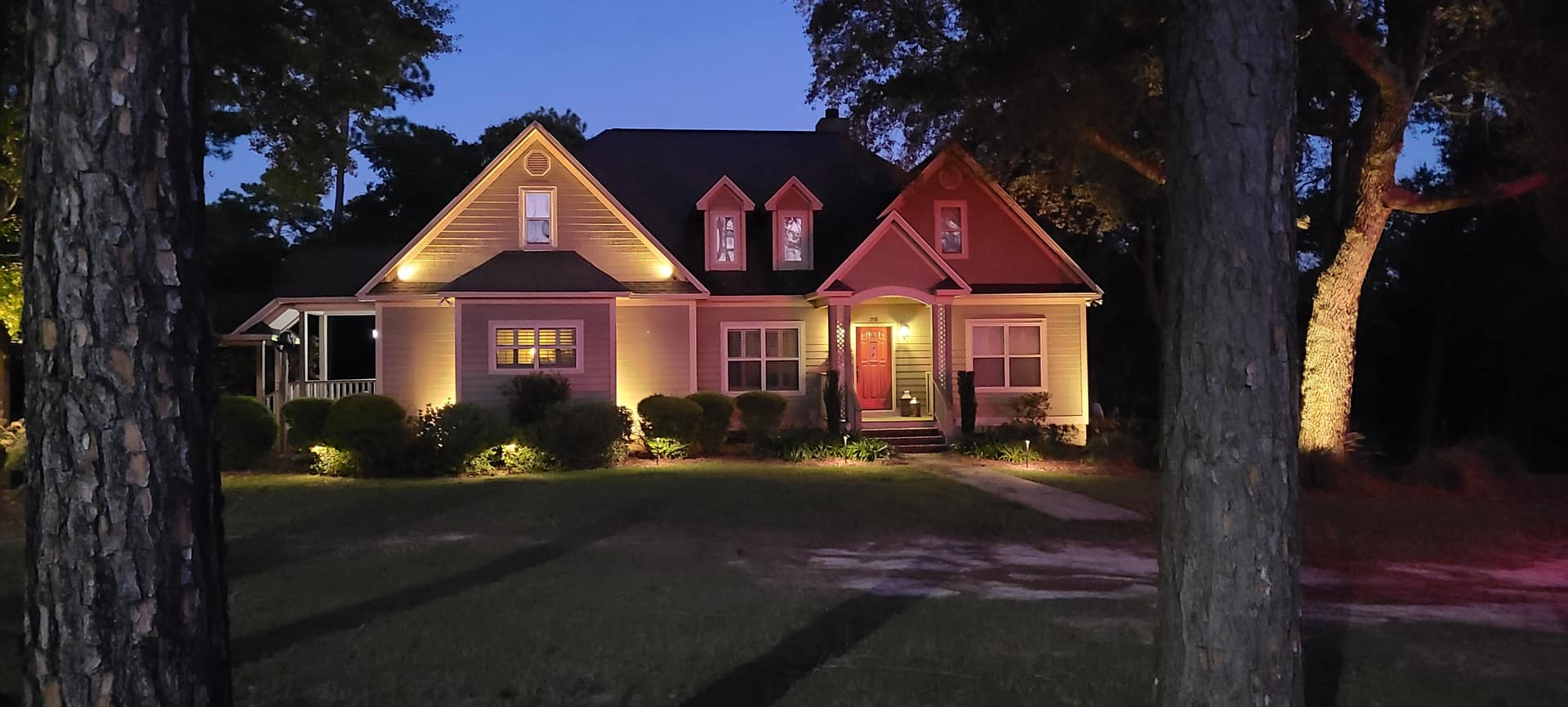 Cottage-style home in Jefferson, GA surrounded by pines with warm landscape lighting