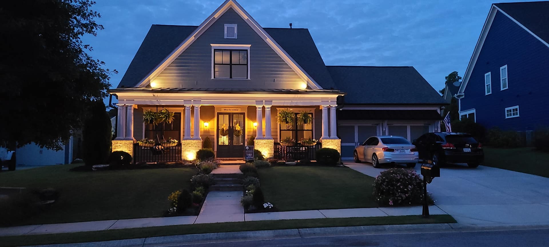Craftsman home with uplit porch columns and a warm, welcoming entry