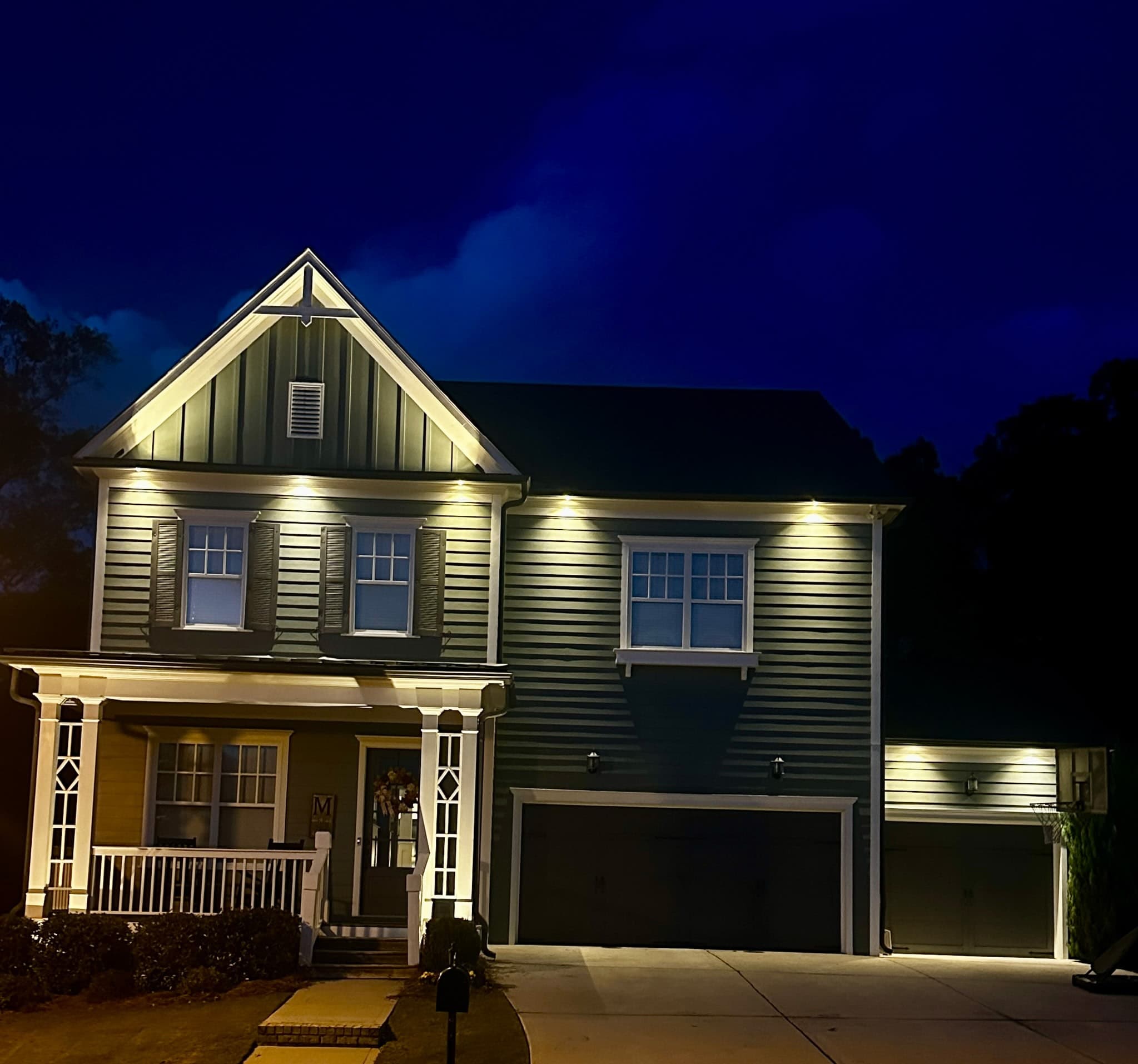 Craftsman home in Hoschton, GA with warm facade and landscape lighting at dusk